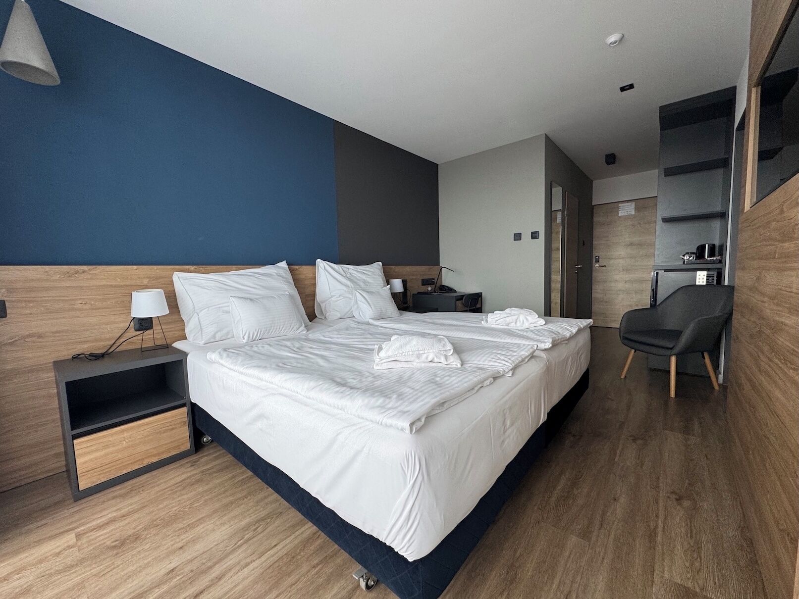 Una habitación de hotel moderna con una cama grande, mesitas de noche, un escritorio y una silla.