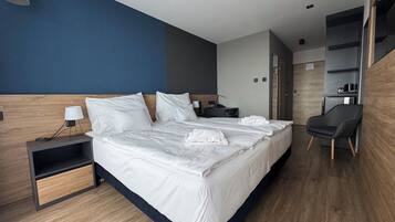 Una habitación de hotel moderna con una cama grande, mesitas de noche, un escritorio y una silla.