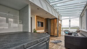 A modern spa room with a glass ceiling, a massage table, a wooden bench, and a view of the outdoors. - Hotel Szieszta (Sopron)