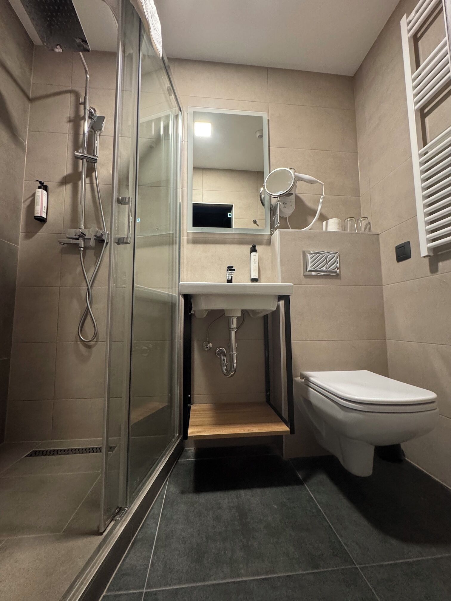 Ein modernes Badezimmer mit Duschkabine aus Glas, Waschbecken mit Spiegel und Toilette.