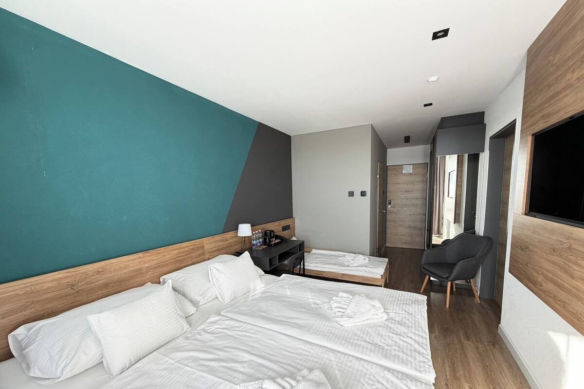 Quarto de hotel moderno com uma cama grande, uma escrivaninha e uma cadeira.