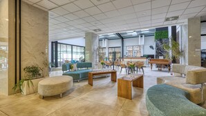 A spacious lobby with a modern design, featuring a mix of seating areas, a coffee table, and a large plant. - Hotel Szieszta (Sopron)