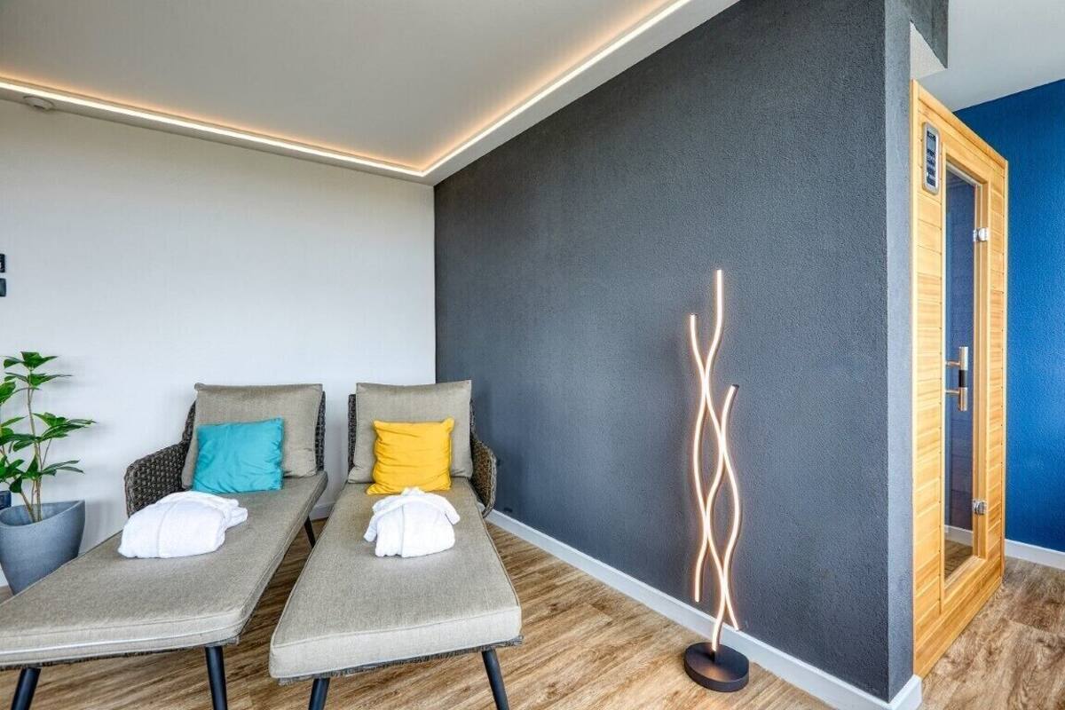 Um quarto de spa com duas mesas de massagem, uma luminária fixada na parede e uma porta de madeira.