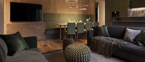 Ein modernes Wohnzimmer mit einer Couch, einem Hocker sowie einem Essbereich mit Stühlen und einem Tisch.