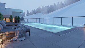 Un área de piscina exterior moderna con barandilla de vidrio, asientos y vistas a un paisaje nevado.