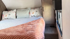 A compact bedroom with a bed, pillows, and a blanket. - Toy Hauler Vengence Rouge (Brentwood)
