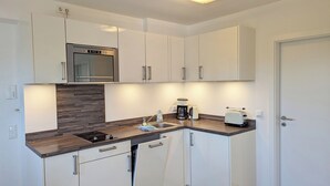 A modern kitchen with white cabinets, a built-in oven, a coffee maker, and a toaster.