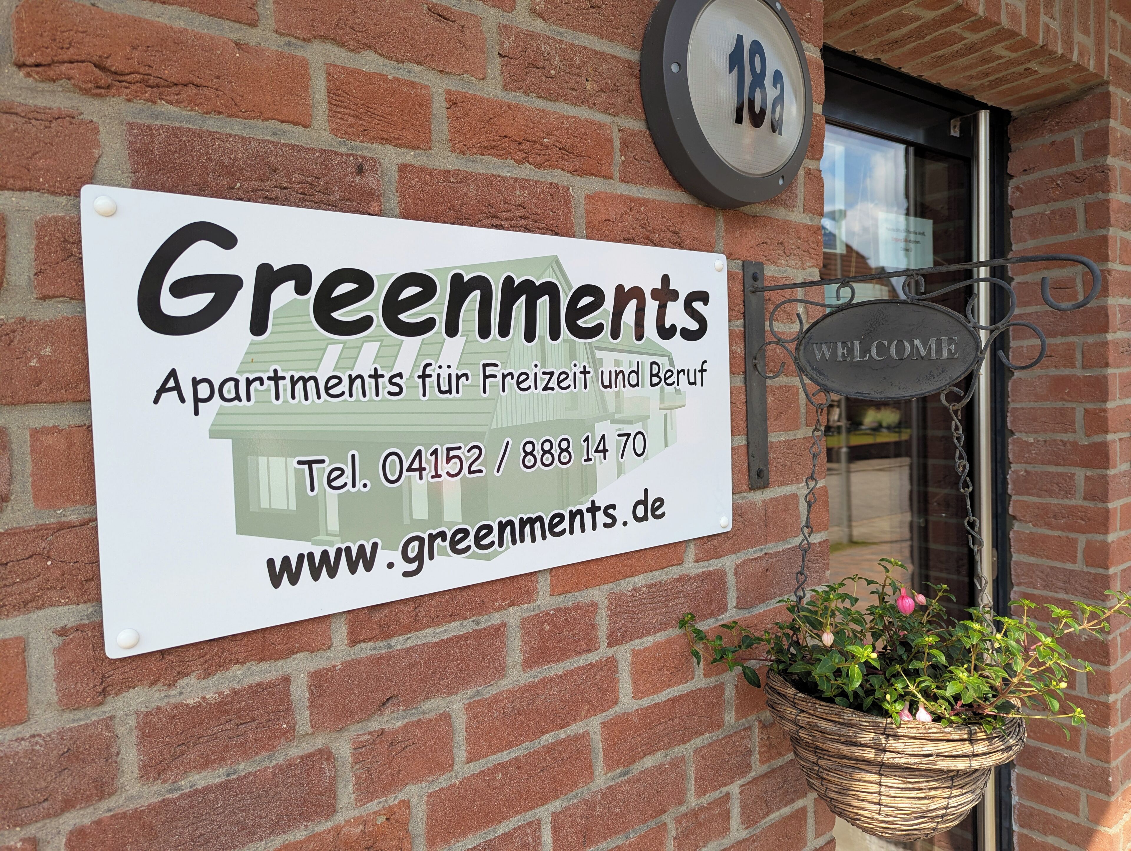 A sign for 'Greenments Apartments for Leisure and Business' with contact information and a website URL.