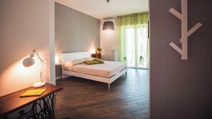 A bedroom with a bed, bedside table, lamp, and a view of the outdoors. - Guest House Colors - by Be Your Home (Civitavecchia)