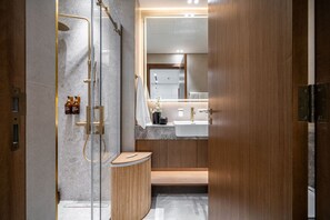 Een moderne badkamer met een douchecabine van glas, een houten wastafelmeubel en een grote spiegel boven de wastafel.