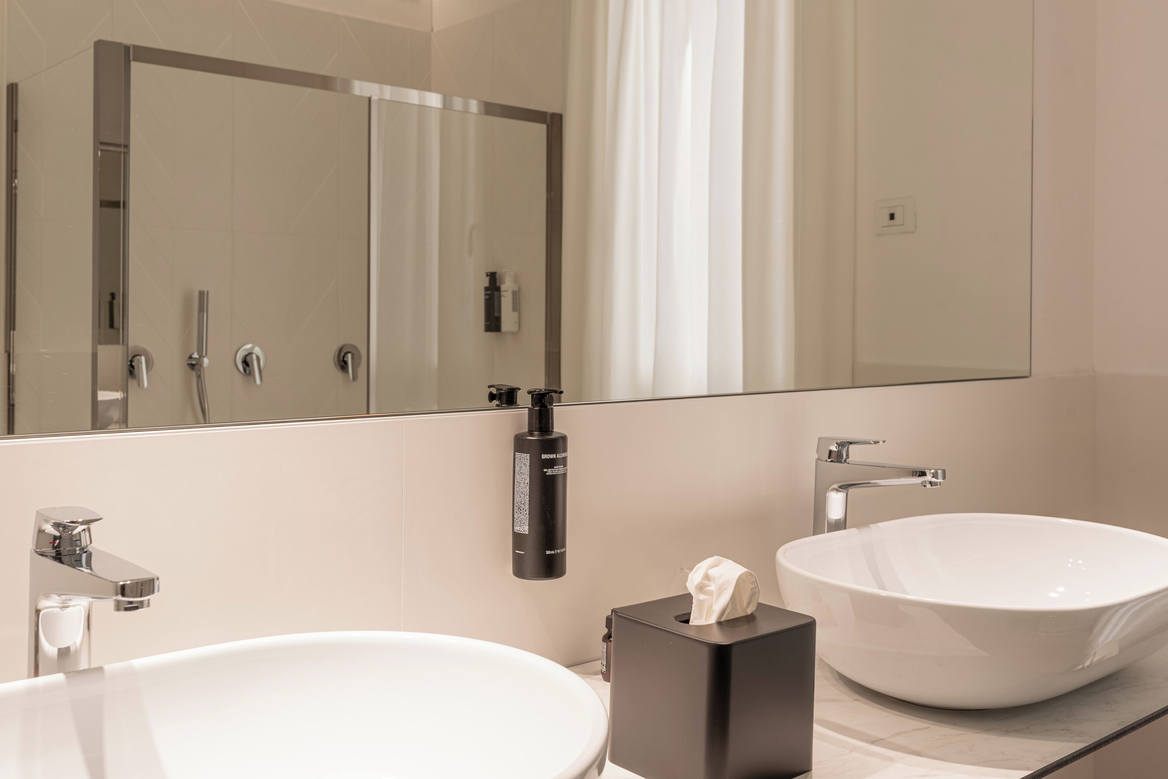 A modern bathroom with a large mirror, a white sink, and a freestanding bathtub.
