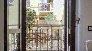 Un balcon avec une balustrade en métal, une table en bois et une chaise.