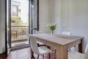 Enjoy meals in this dining area with a large table and comfortable chairs, overlooking the outdoor balcony.
