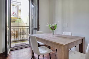 Enjoy meals in this dining area with a large table and comfortable chairs, overlooking the outdoor balcony.