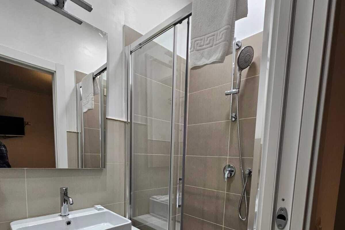 A modern bathroom with a glass-enclosed shower, a white sink, and a mirror above the vanity.