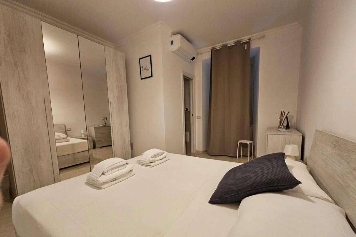 A hotel room with a large bed, a wardrobe, a small table with a lamp, and a picture on the wall.