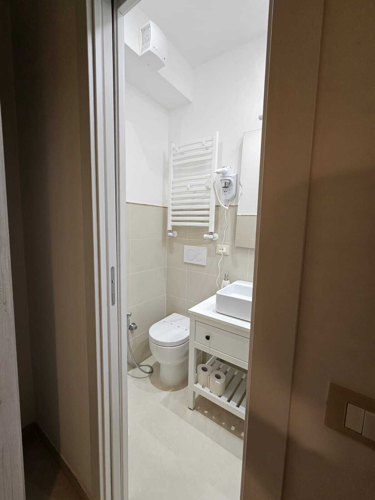 A bathroom with a toilet, sink, and towel rack.