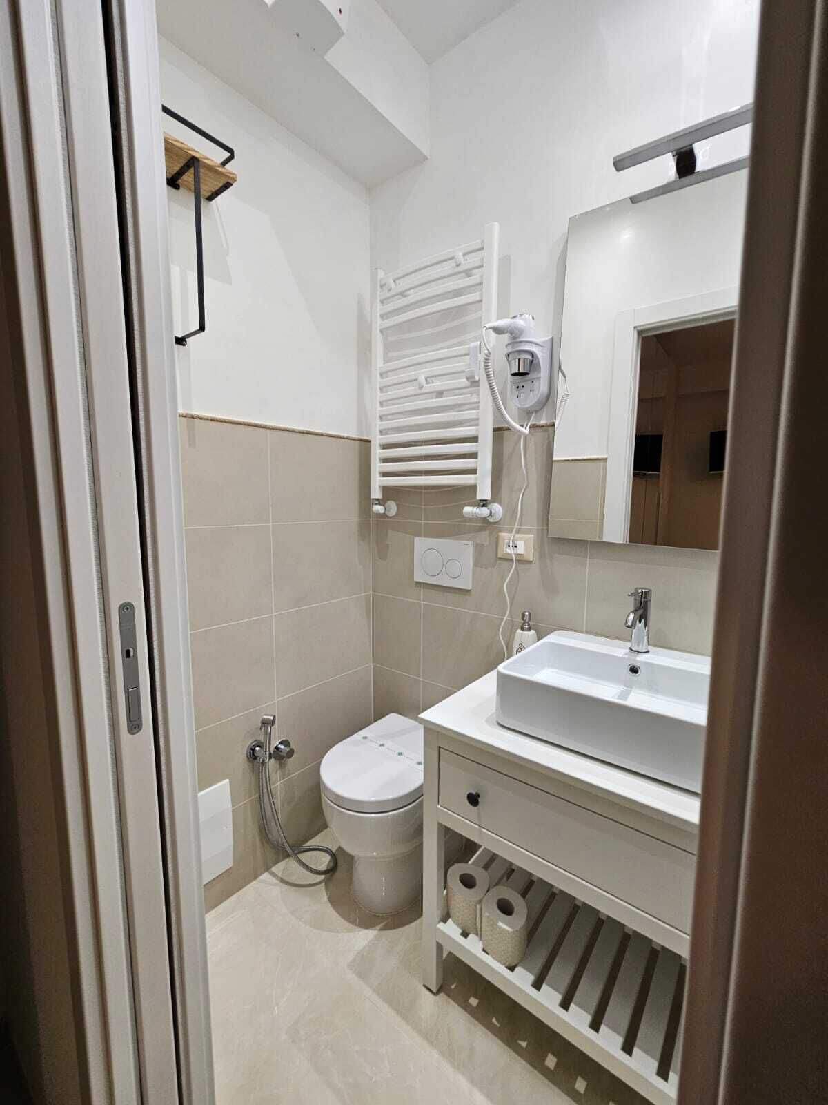 A modern bathroom with a toilet, bidet, and a sink with a mirror above it.