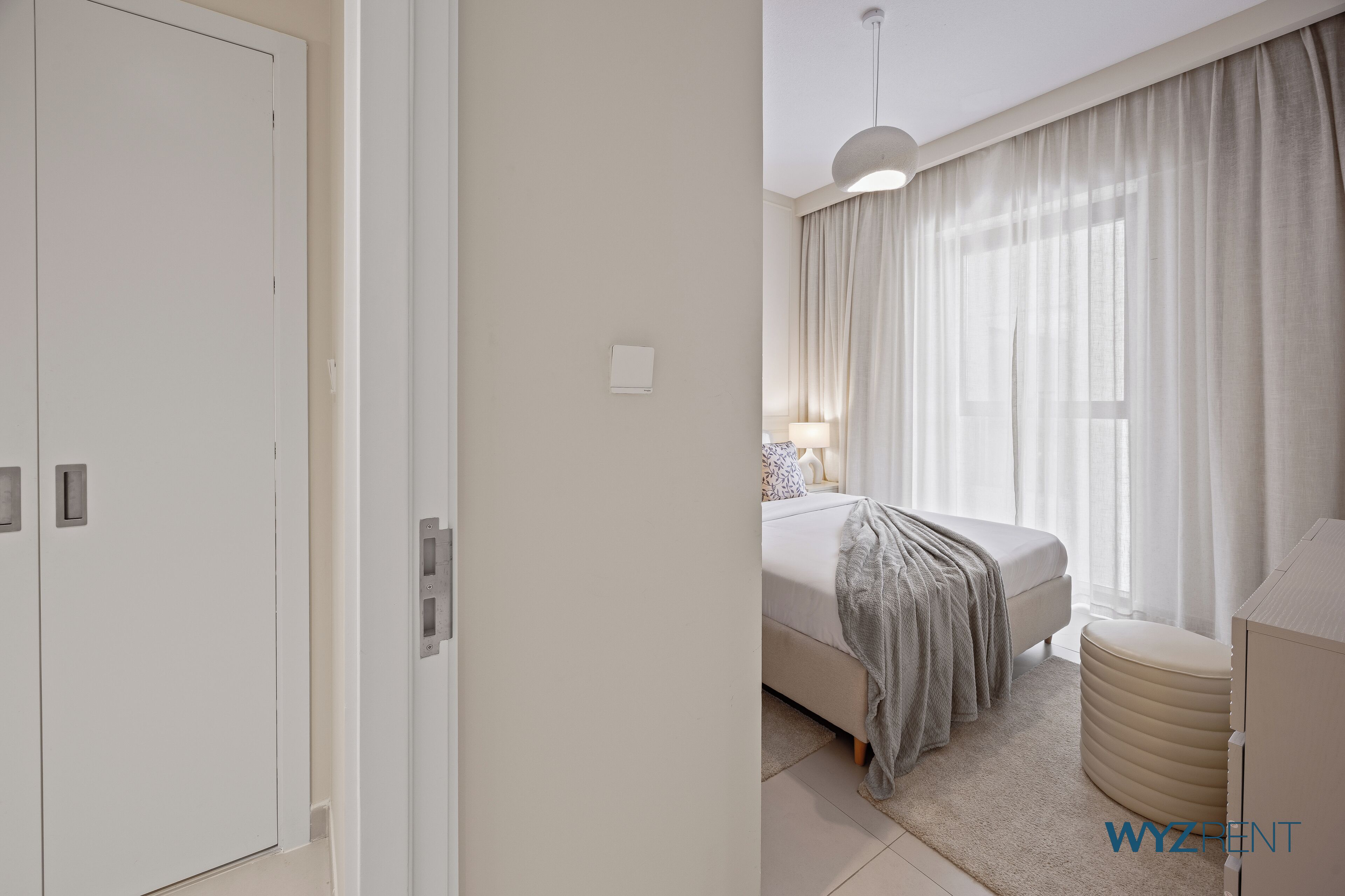 A modern bedroom with a bed, bedside table, and curtains.