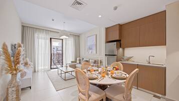 Una cocina moderna con armarios de madera, un comedor con una mesa redonda y sillas, y vistas al balcón.