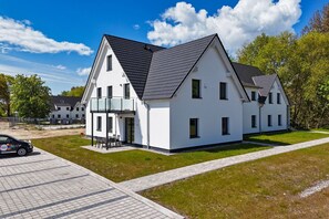 A modern two-story house with a balcony, a paved driveway, and a well-maintained lawn. - Beachfront vacation rental with a balcony; access to the pool and sauna - Rex Rugia - Rex Rugia (Göhren)