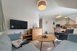 A modern living room with a flat-screen TV, a wooden coffee table, and a sofa.
