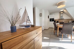 Una cucina moderna con zona pranzo, mobili in legno e un modellino di una barca a vela sul bancone.