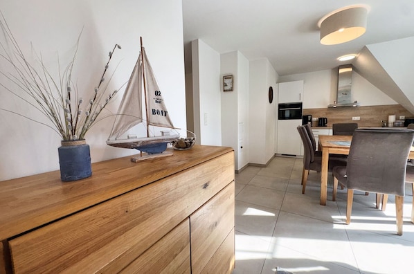 A modern kitchen with a dining area, wooden cabinetry, and a sailboat model on the counter.
