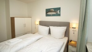 A hotel room with a bed, two bedside tables with lamps, a wardrobe, and a wall-mounted artwork of a fish.