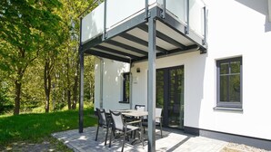 A modern house with a covered patio, a dining table, and chairs.