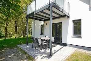 A modern house with a covered patio, a dining table, and chairs.