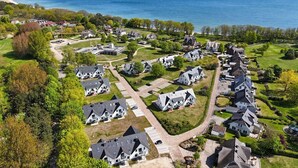Ett flygbildsbild av ett bostadsområde med hus, vägar och en strand i bakgrunden.