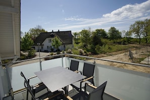 A balcony with a table and chairs, overlooking a house and greenery. - Beachfront vacation rental with a balcony; access to the pool and sauna - Rex Rugia - Rex Rugia (Göhren)