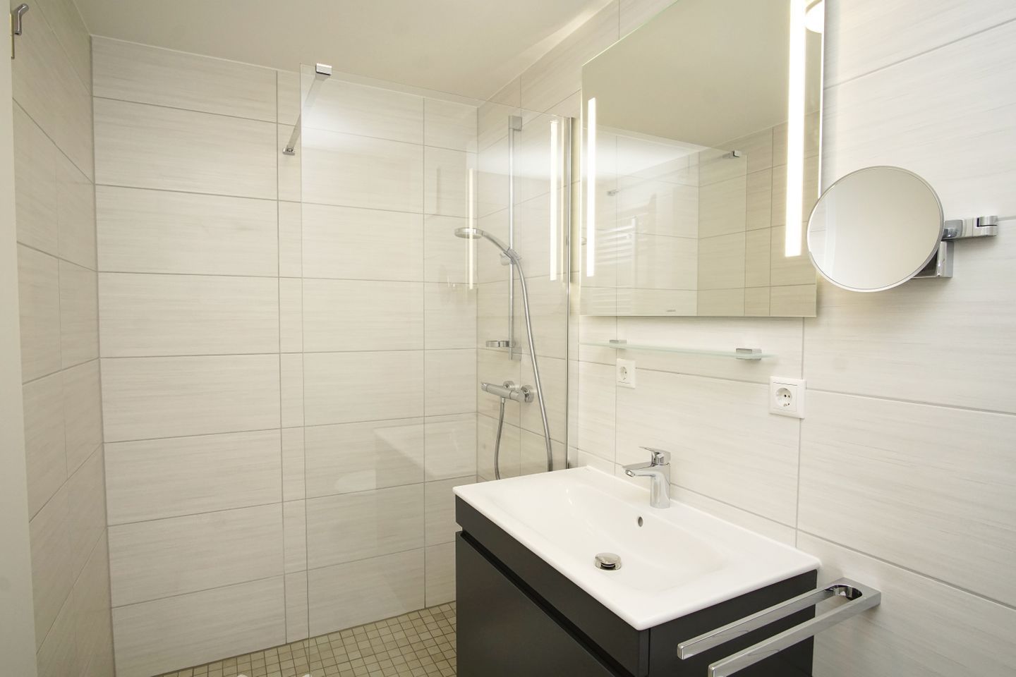 A modern bathroom with a shower, a sink, and a mirror.