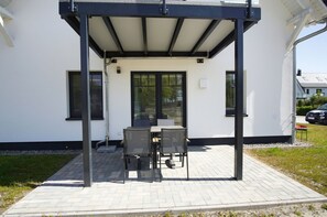 En udendørs patio med overdækket siddeområde, et bord og stole.