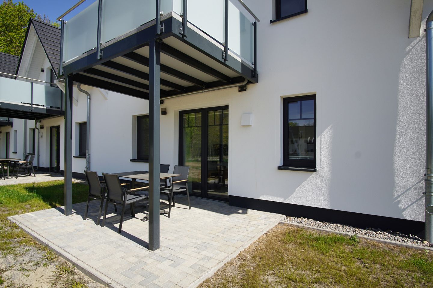 A modern building with a covered patio area featuring a table and chairs.