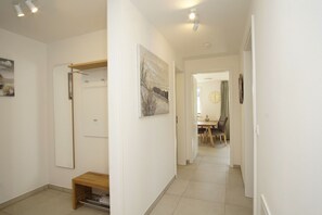 Un couloir avec un banc en bois, un porte-manteau et un tableau accroché au mur.