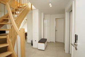 A modern interior with a wooden staircase, a bench, and a door with a handle.