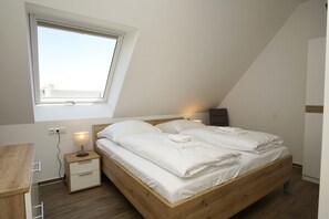 Une chambre à coucher moderne avec un plafond en pente, une grande fenêtre, un lit en bois, des tables de chevet avec des lampes et un bureau.