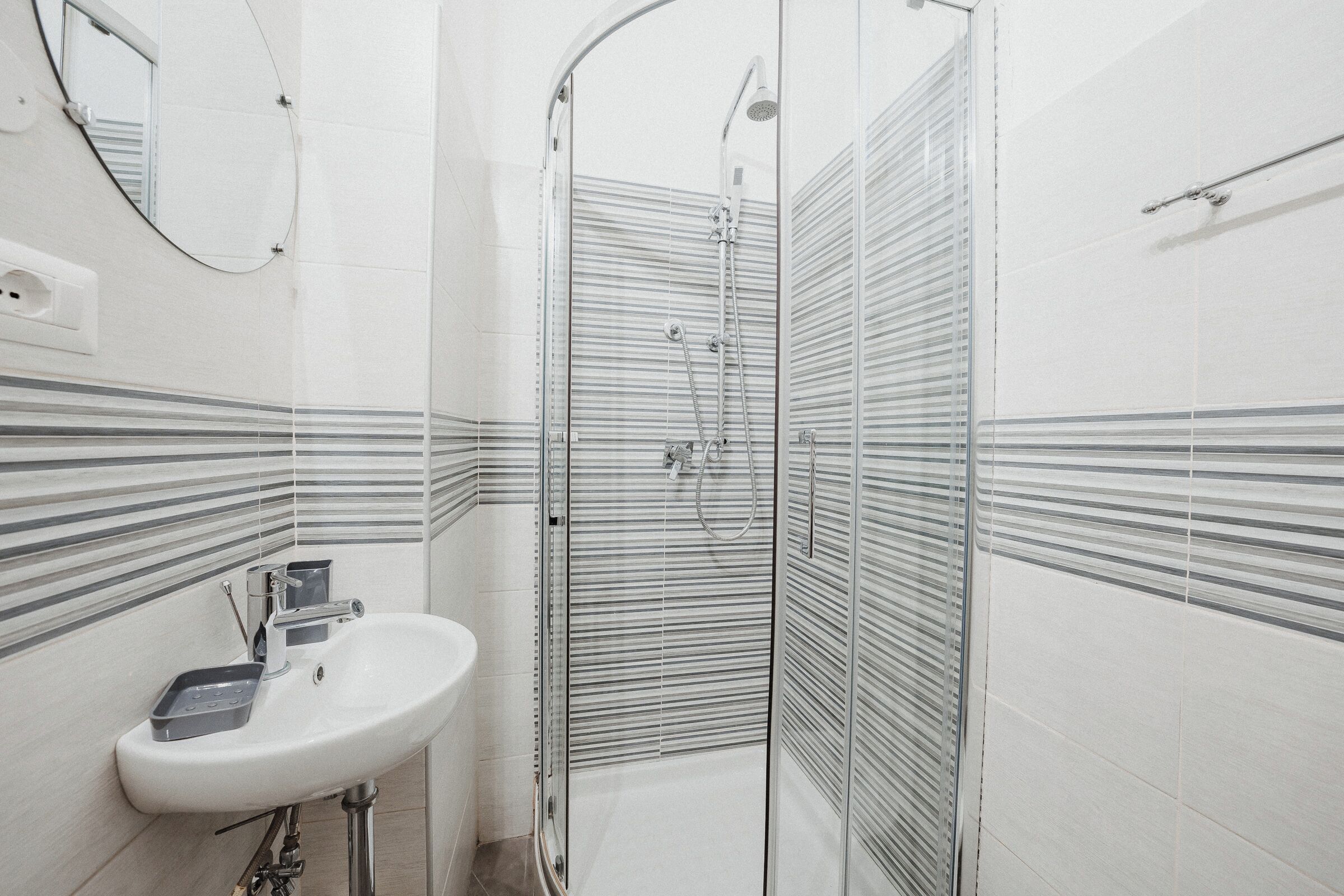 A bathroom with a sink, mirror, and shower enclosure.