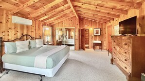 Een houten slaapkamer met een bed, een dressoir en een televisie.