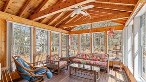 A wooden deck with a ceiling fan, a sofa, and chairs.