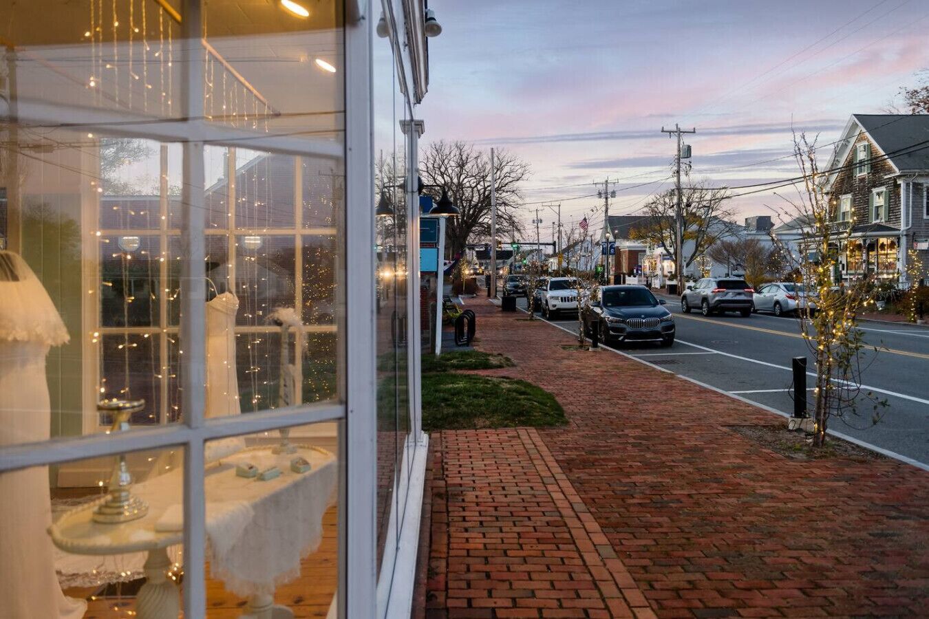 A brick-paved sidewalk adjacent to a street with parked cars.