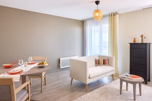 Un salon moderne avec un canapé, une table à manger et une petite table d’appoint.