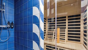 Une salle de bain avec des carreaux bleus et un espace sauna en bois.