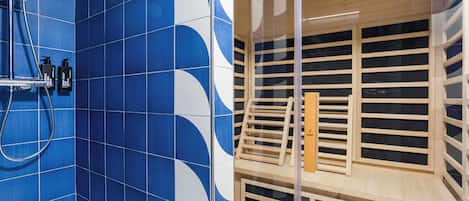 A bathroom with blue tiles and a wooden sauna area.