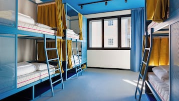 Habitación con literas, una escalera, ventana con cortinas y techo azul.