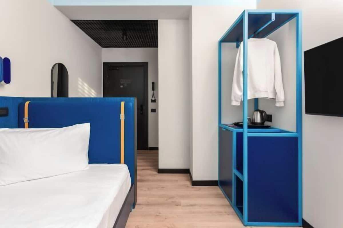 Ett modernt hotellrum med en säng, en blå garderob och en vit handduk som hänger på garderoben.