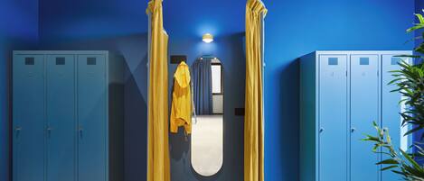 A room with blue lockers, a yellow curtain, and a mirror.