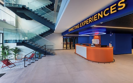 A modern lobby with a reception desk, glass railings, and a staircase.